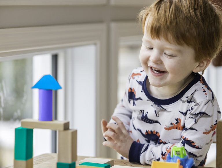 Toddler smiling while stacking colorful blocks