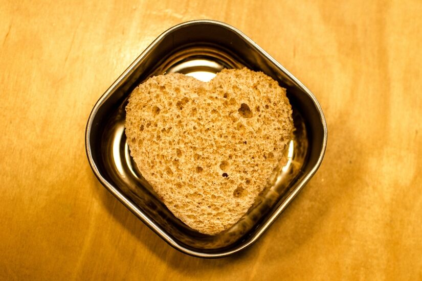 A heart-shaped sandwich sits in a metal dish.