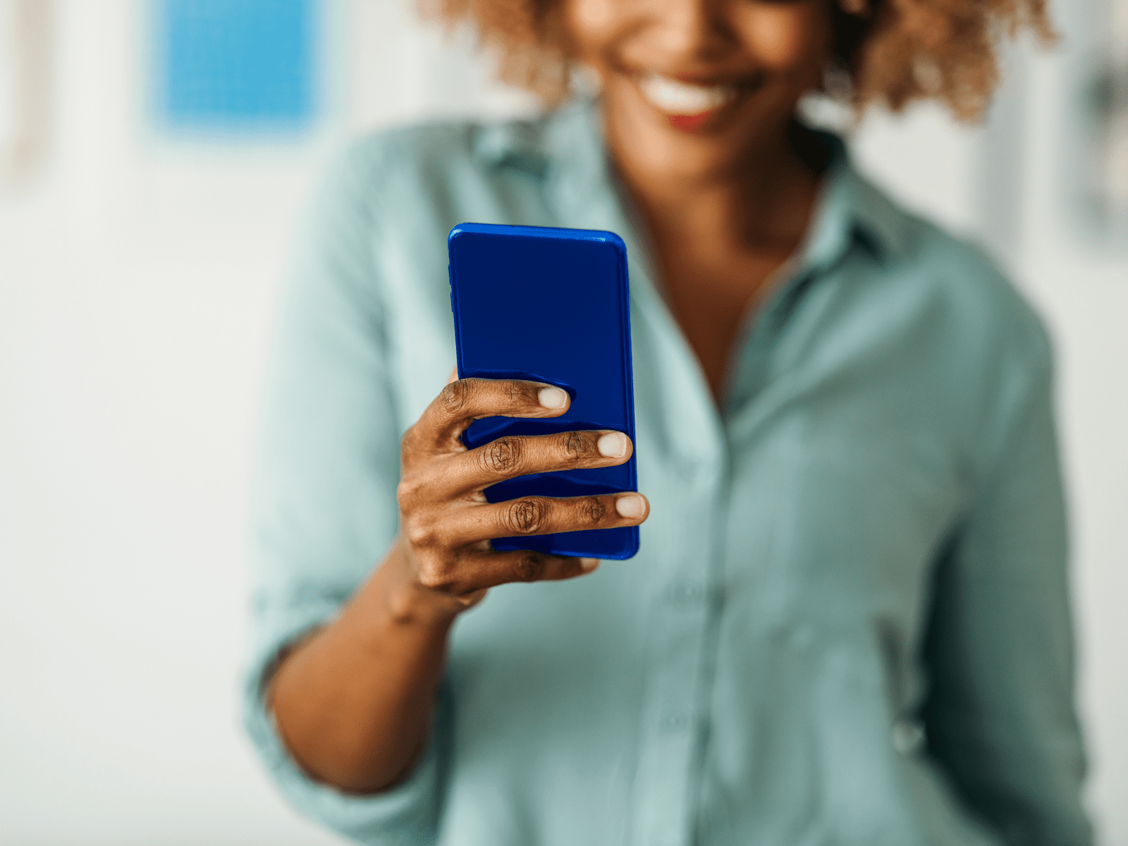 Woman smiling holding blue phone