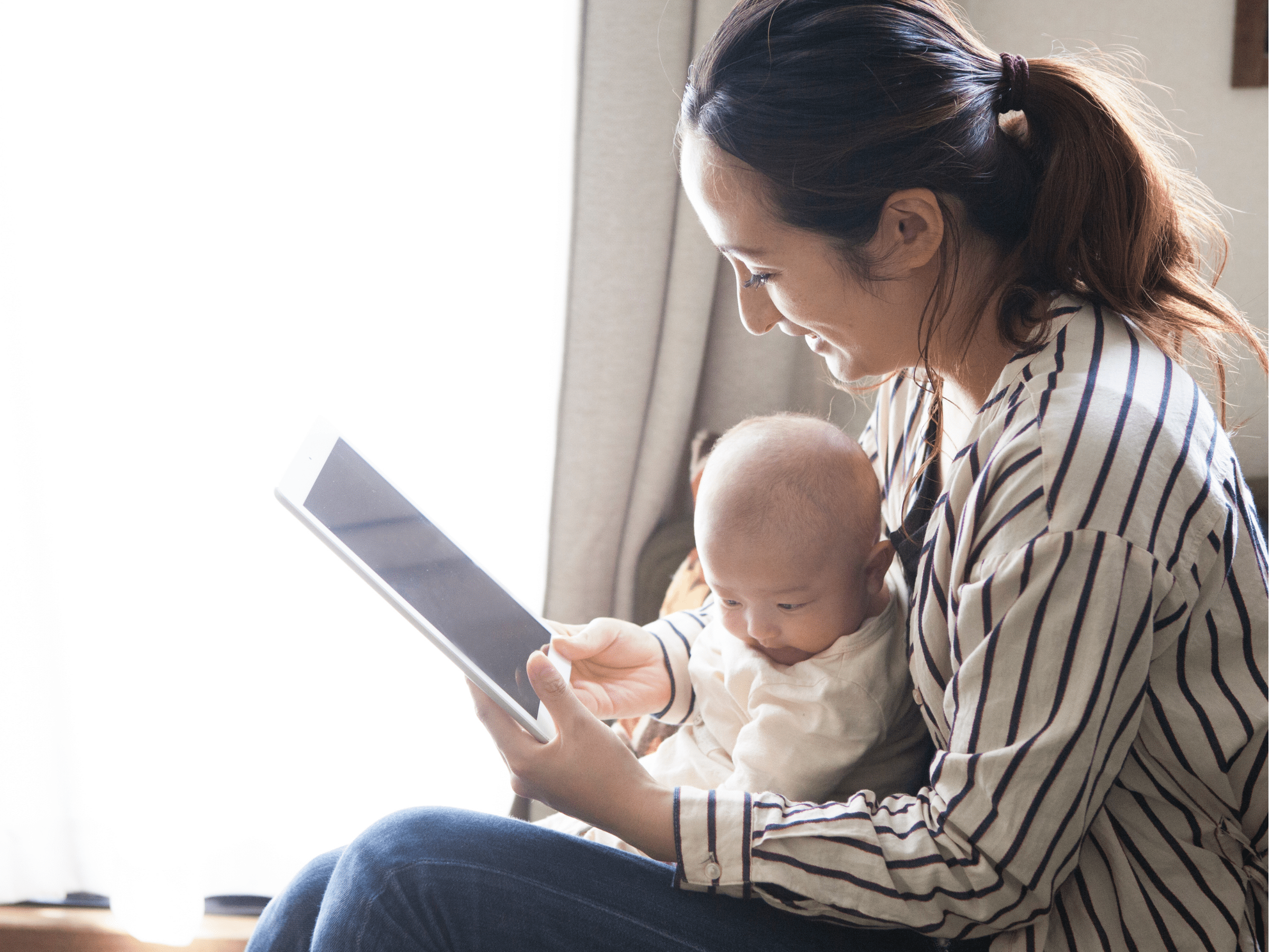 woman holding baby looking at ipad